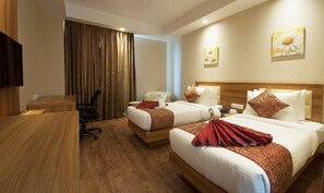 Une chambre d’hôtel avec deux lits, un bureau, une chaise et un téléviseur.
