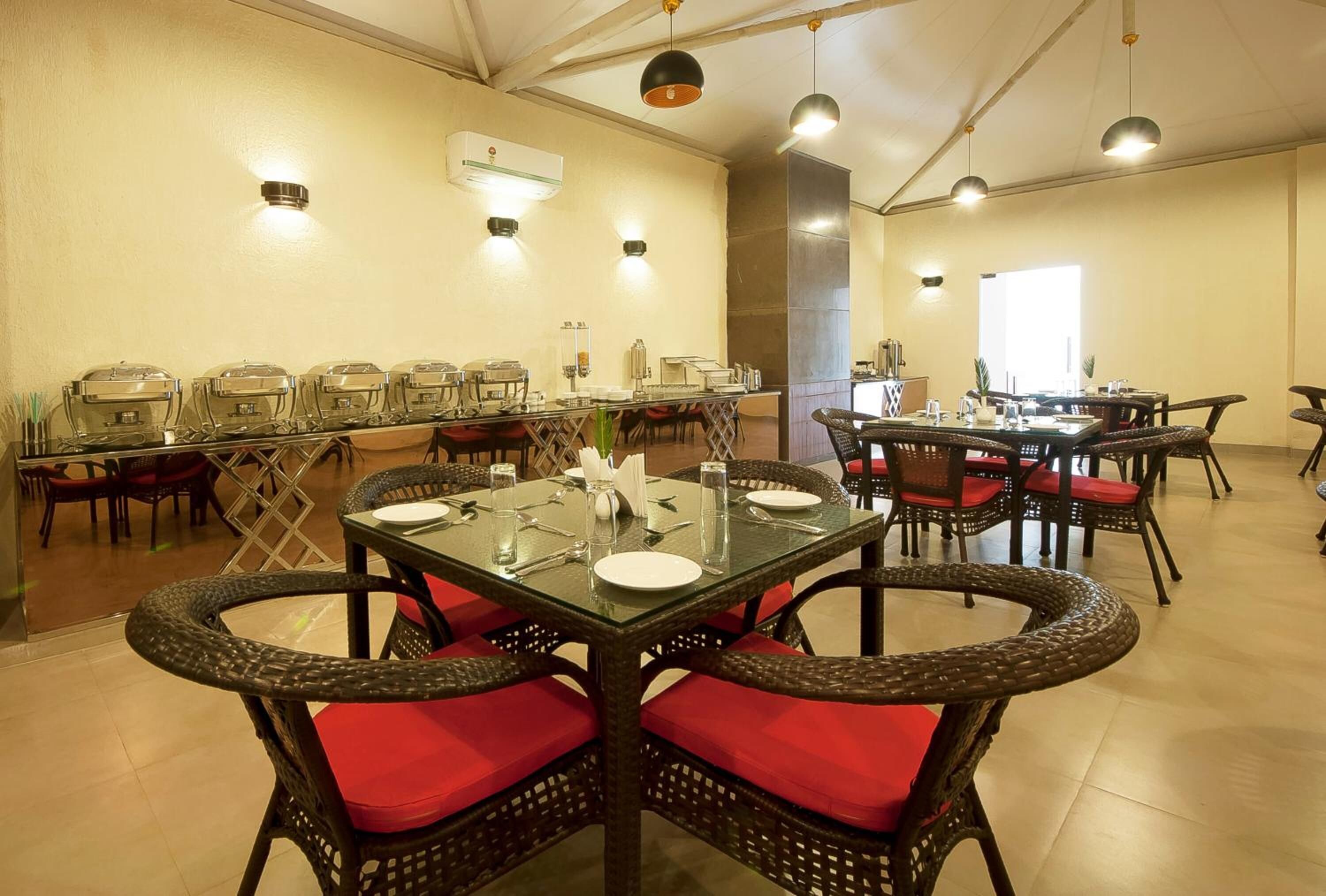 A dining area with multiple tables and chairs, buffet setup, and ceiling lights.