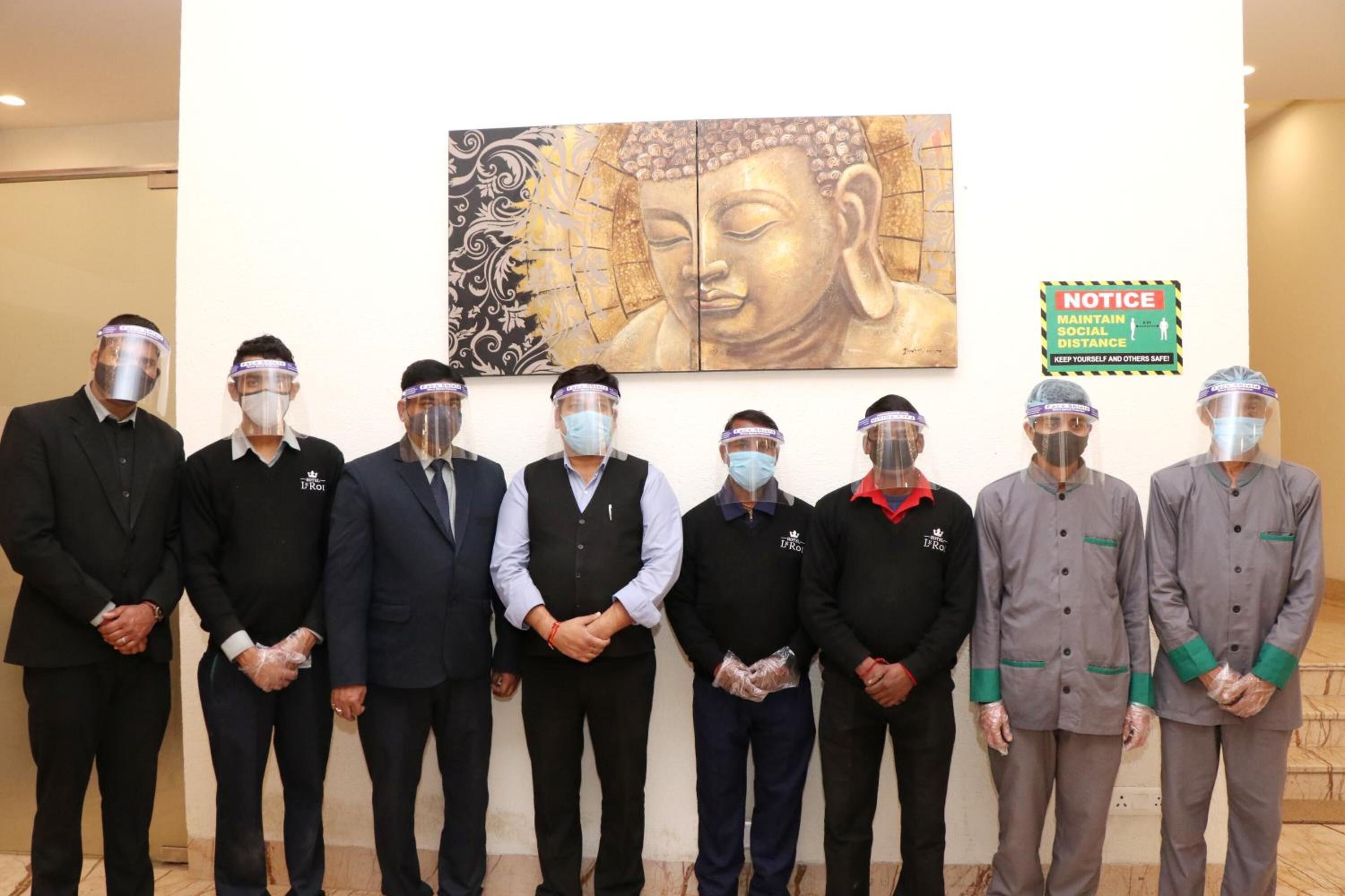 Un grupo de personas de pie en una habitación con un cuadro de Buda y un letrero en la pared.