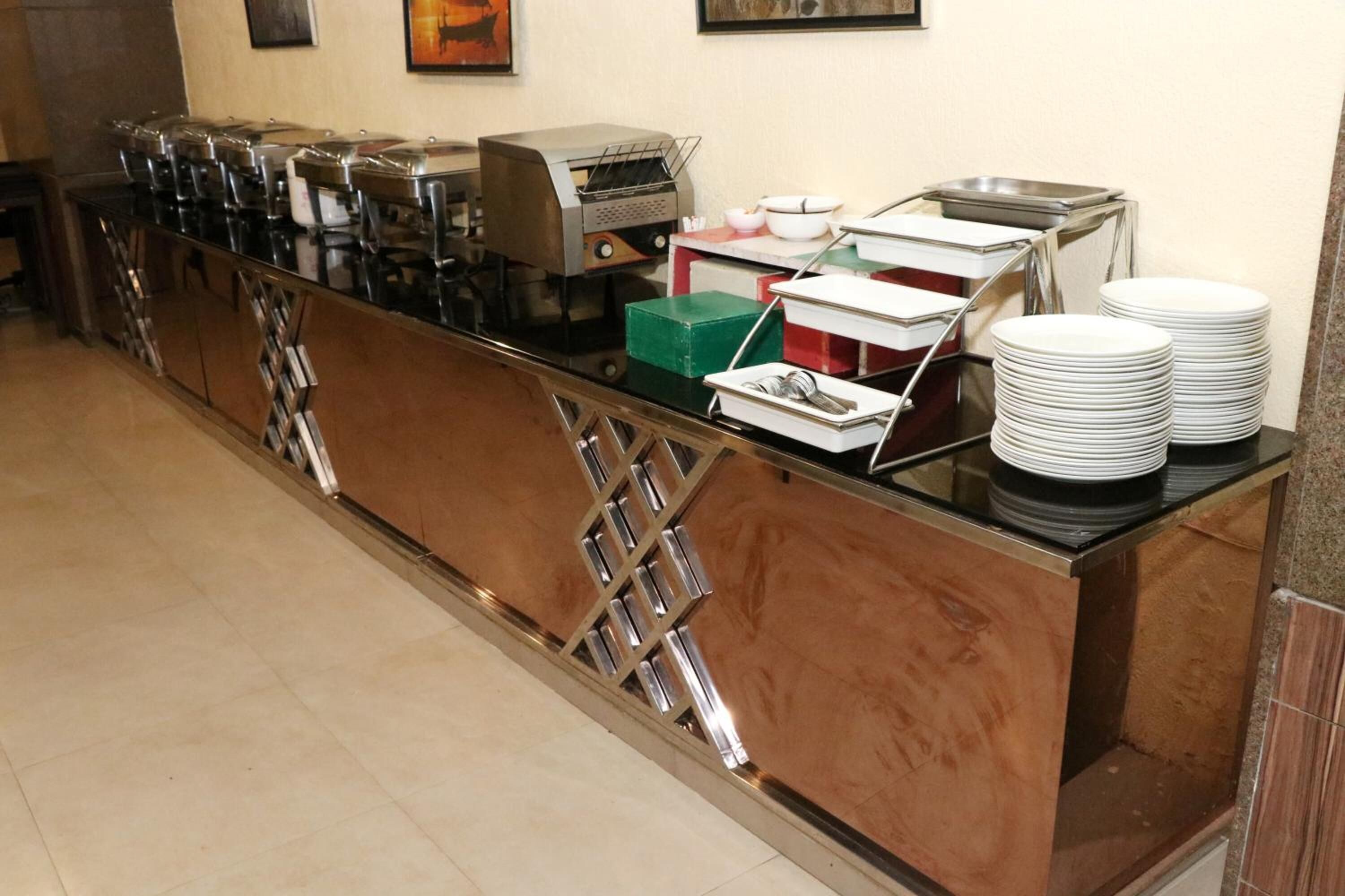 A buffet setup with multiple food dispensers and stacked plates.