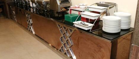 A buffet setup with multiple food dispensers and stacked plates.