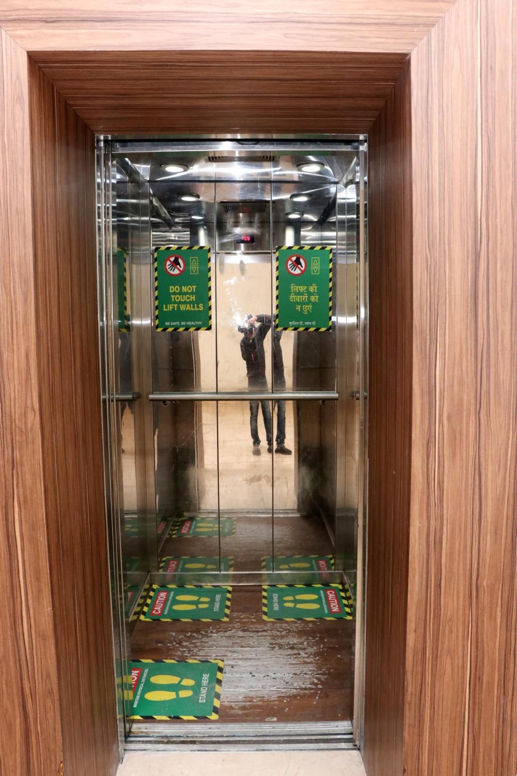 Interior de un ascensor con señales de precaución y una persona en su interior.