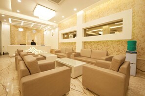 Un hall d’hôtel comprenant un comptoir d’accueil, des canapés, une table basse et un distributeur d’eau.