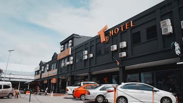 Een hotel met een opvallend 'HOTEL'-bord, meerdere airconditioners en geparkeerde auto's ervoor.
