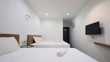 A hotel room with two beds, a TV mounted on the wall, and a small table with a bottle and glasses.