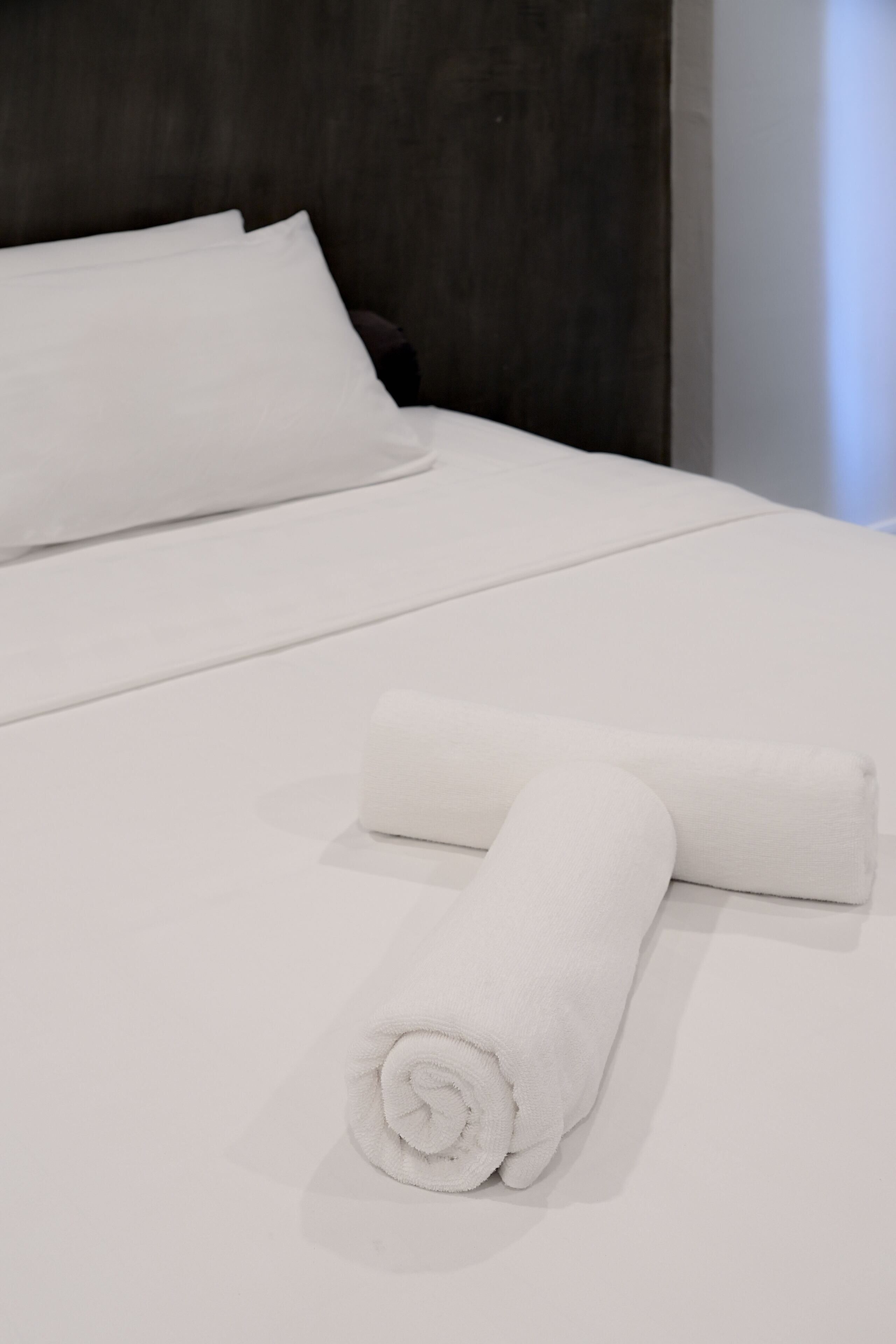 A neatly made bed with white linens and a rolled towel.