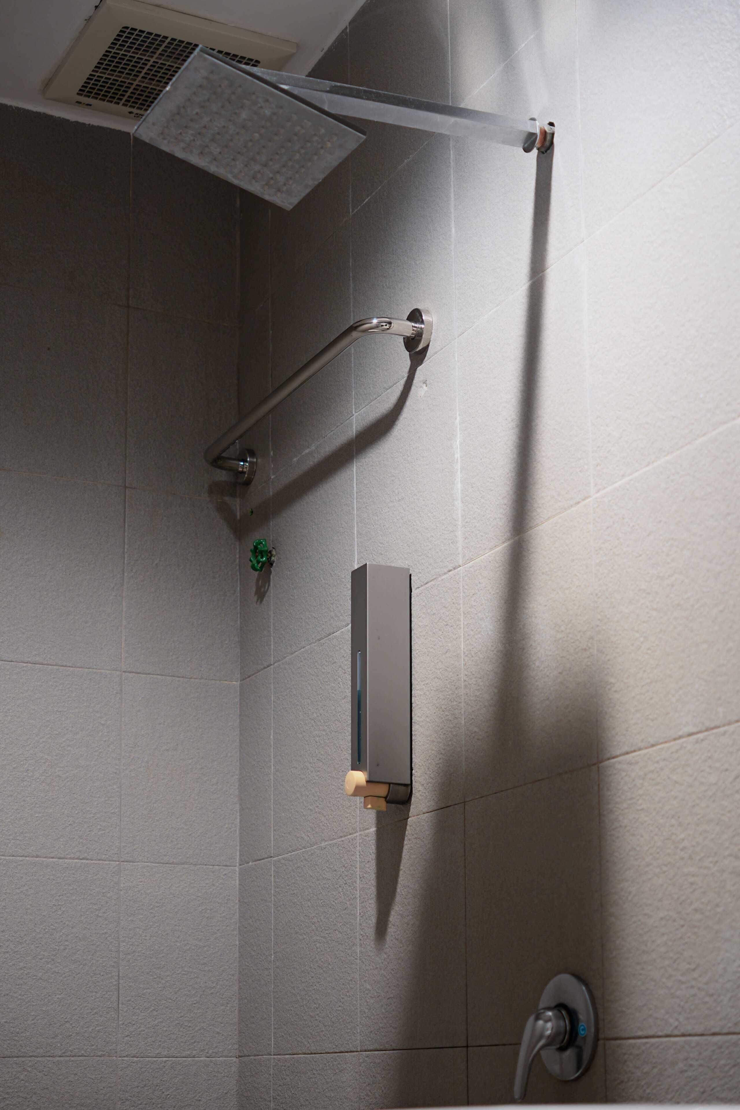 A modern shower with a handheld showerhead, a wall-mounted control panel, and a floor-mounted faucet.