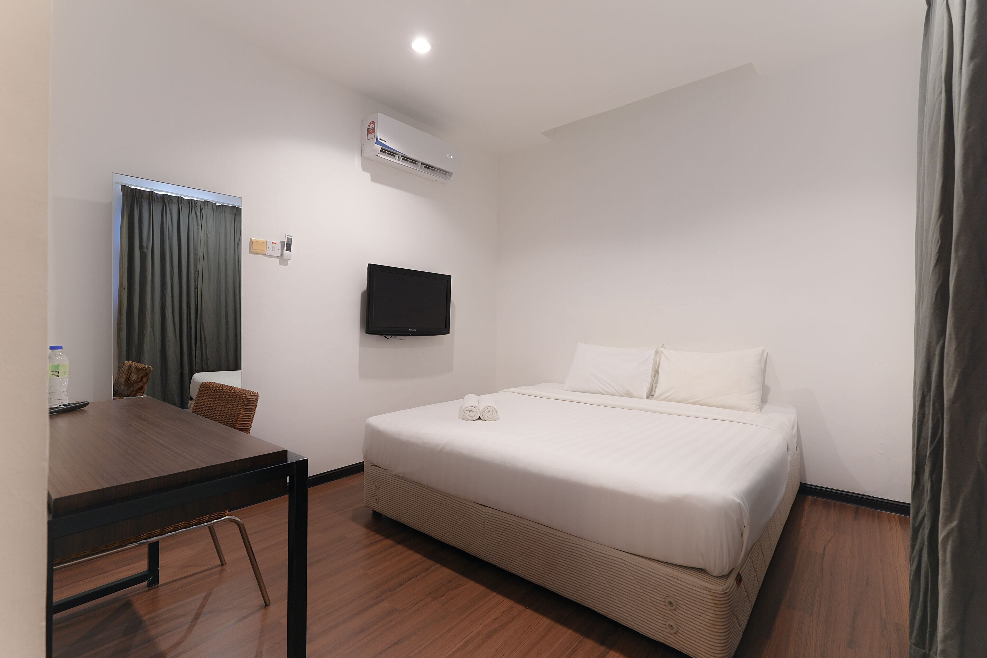 Une chambre d’hôtel équipée d’un lit, d’un téléviseur fixé au mur, d’une table avec des chaises et d’un appareil de climatisation.