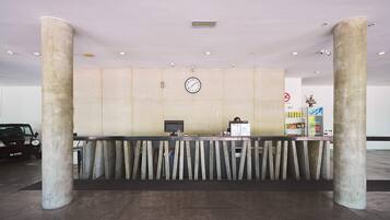 A reception area with a reception desk, a clock, and a wall-mounted security camera.