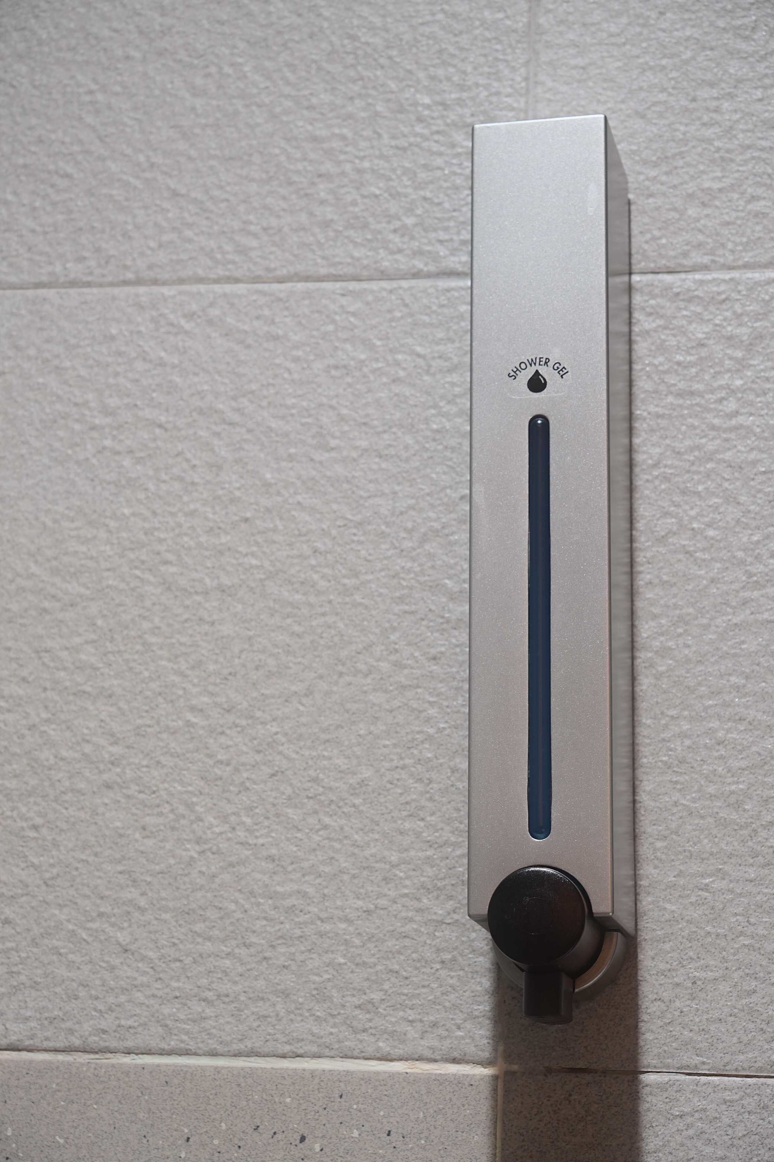 Un panneau de commande de douche fixé sur un mur recouvert de carreaux.