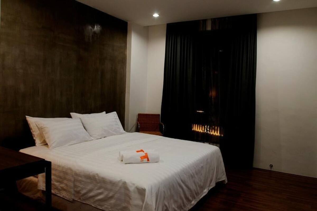 Una habitación de hotel con una cama grande, una mesita pequeña, una silla y una chimenea.