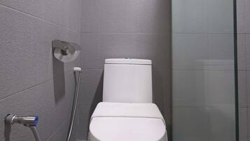 A modern bathroom with a toilet, a glass shower enclosure, and a grab bar.
