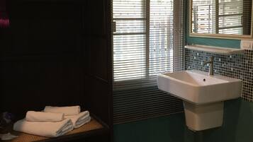 A bathroom with a wooden cabinet, a sink, and a window with blinds.