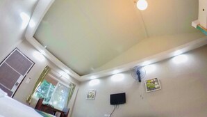 A room with a white ceiling, recessed lighting, a wall-mounted TV, and a ceiling fan. - Q Zone Boutique (Ayutthaya)