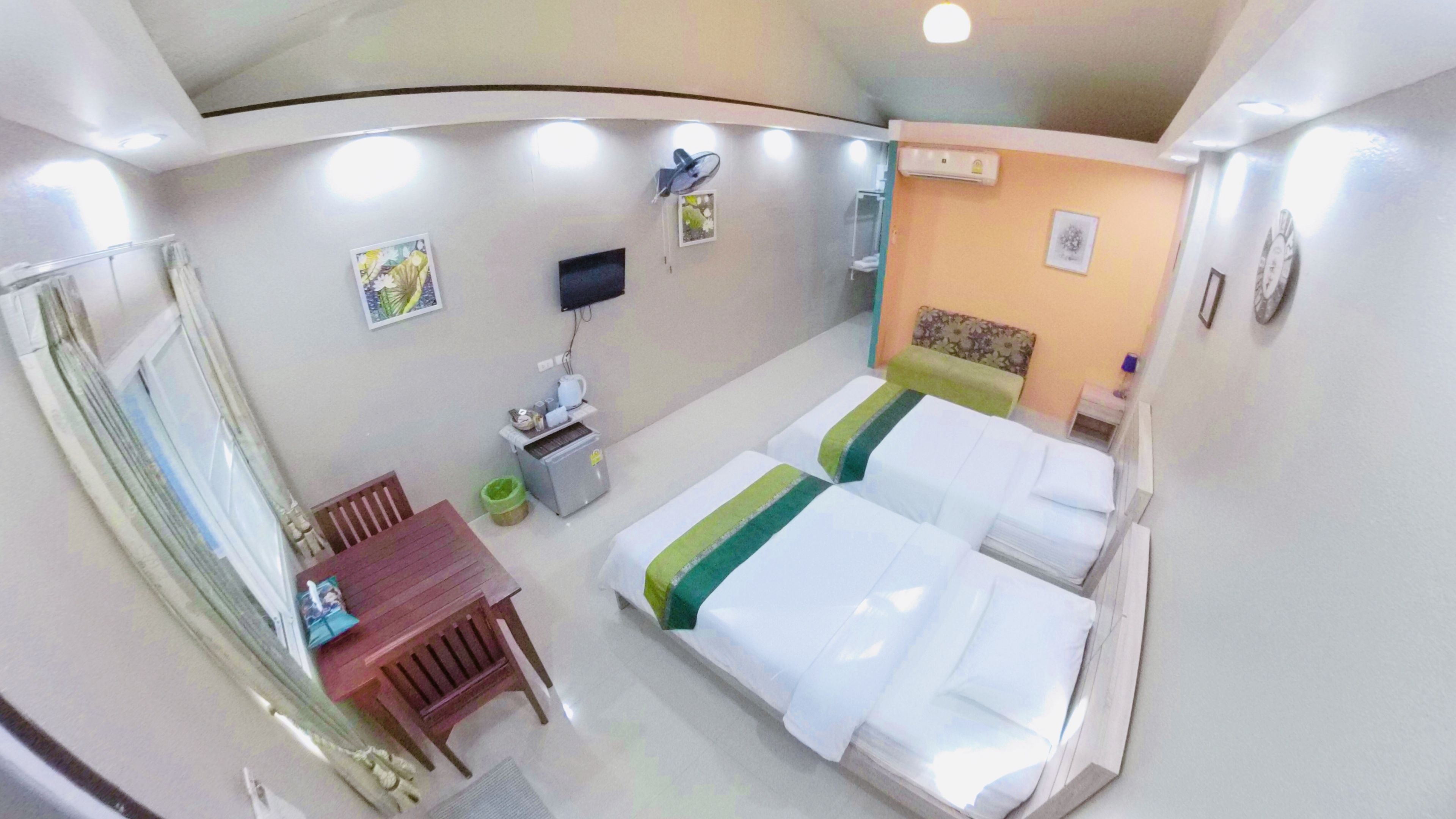 A hotel room with two beds, a desk, a chair, a TV, and a window.