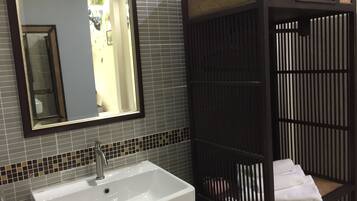 Un baño con un lavamanos blanco, un espejo y un mueble de madera oscura con un estante tejido.