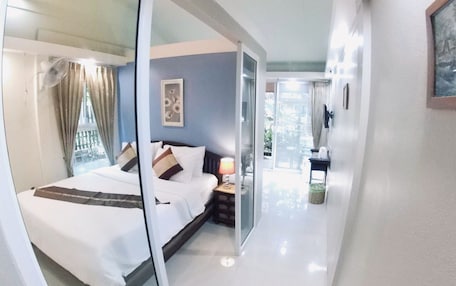 A hotel room with a bed, a nightstand, a lamp, and a window with curtains.
