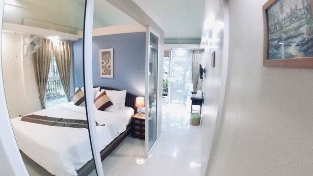 A hotel room with a bed, a nightstand, a lamp, and a window with curtains. - Q Zone Boutique (Ayutthaya)