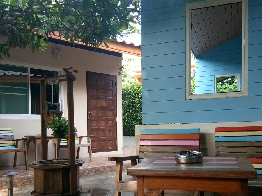 A blue building with a window, a door, and a bench with colorful stripes.