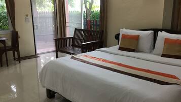 A hotel room with a bed, a chair, a desk, and a window with curtains.