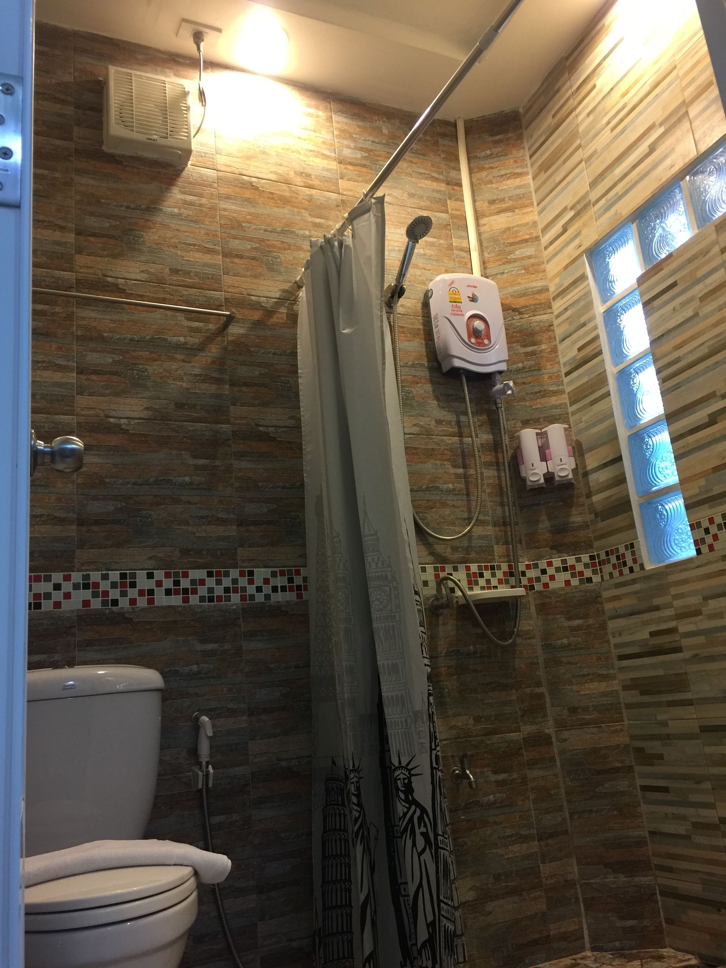 Et badeværelse med brusebad, toilet og hårtørrer.