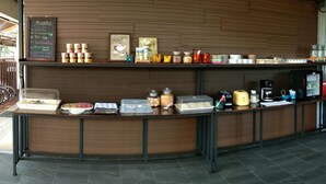 A breakfast buffet counter with various food items and condiments. - Q Zone Boutique (Ayutthaya)