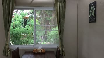 A room with a window, curtains, a table, and a wall-mounted picture.