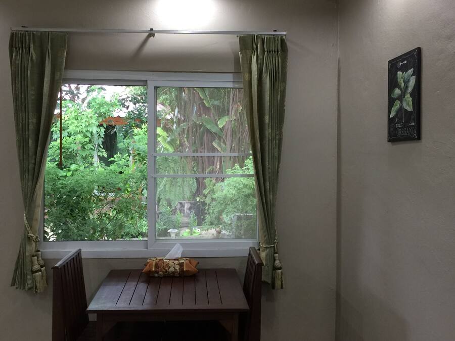 A room with a window, curtains, a table, and a wall-mounted picture.
