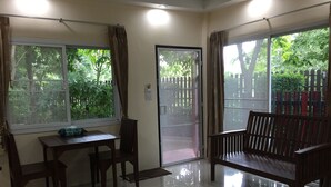 A room with a wooden table and chairs, a bench, and large windows with curtains. - Q Zone Boutique (Ayutthaya)