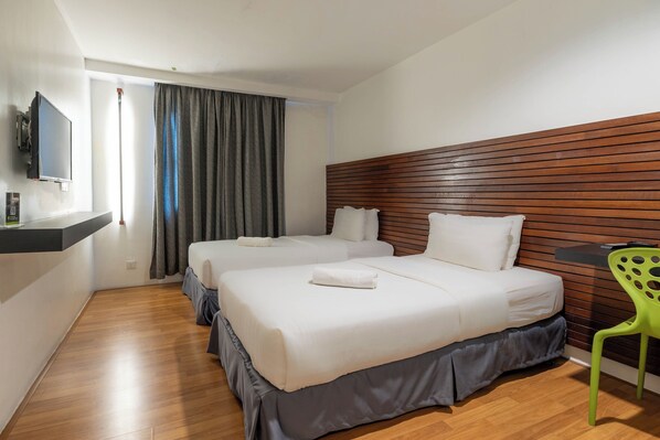 A hotel room with two beds, a wooden headboard, a TV mounted on the wall, and a green chair.