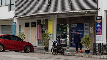 A building with a sign reading "OUM Open University Malaysia" and a red car parked in front.