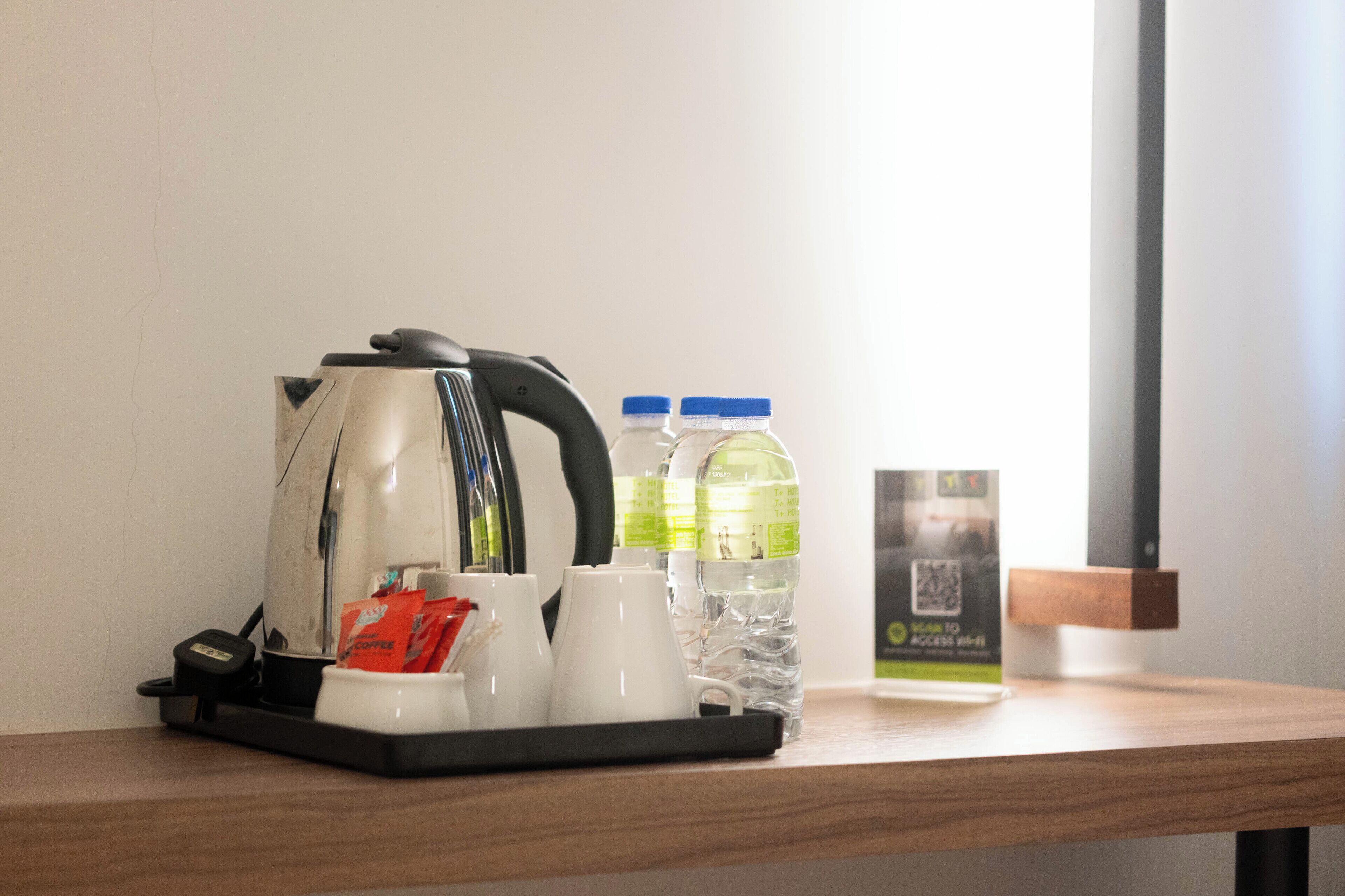 A coffee maker, two bottles of water, a kettle, and a coffee pod on a tray.
