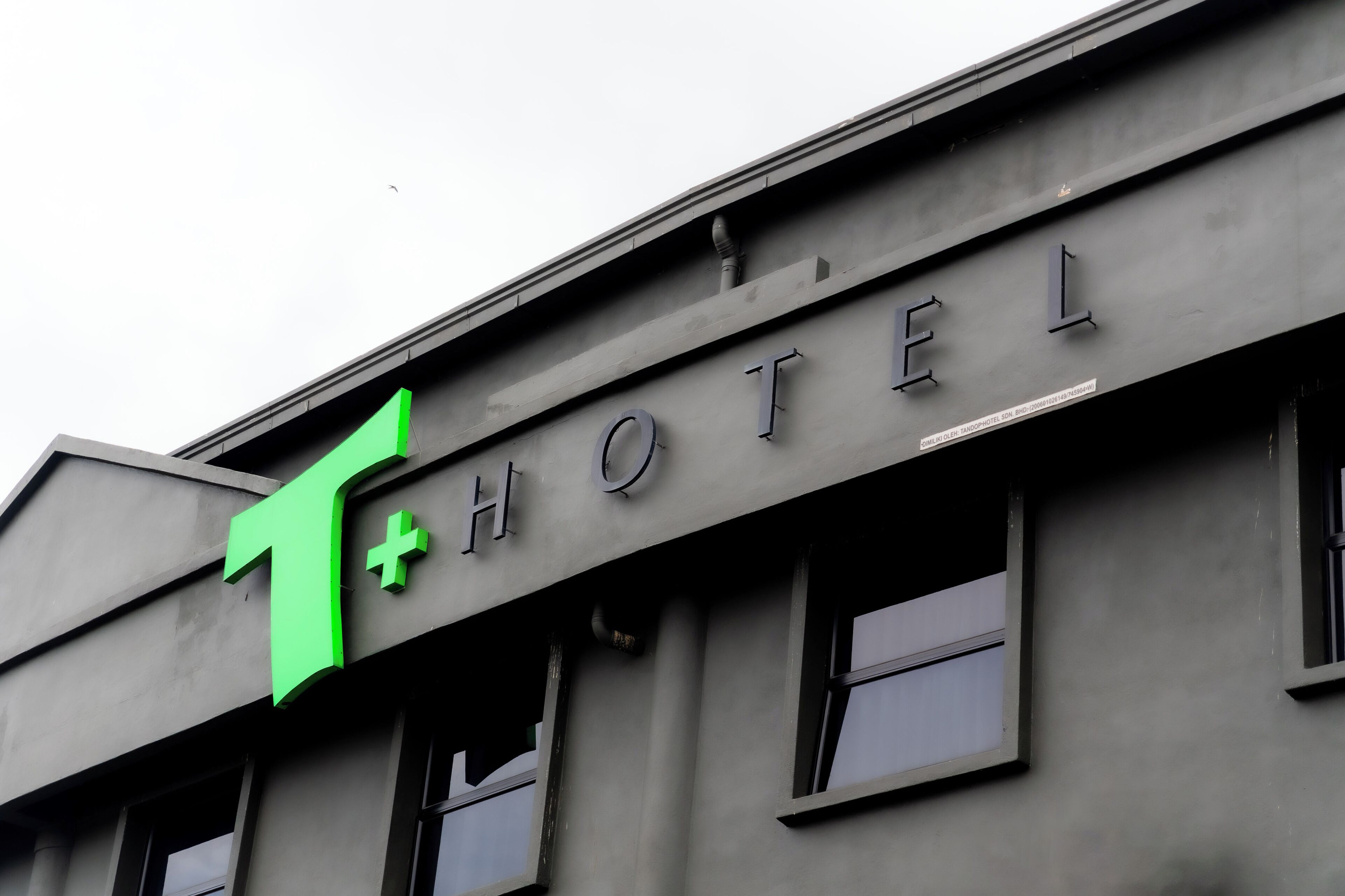 Un edificio con una gran 'T' verde y la palabra 'HOTEL' en la fachada.