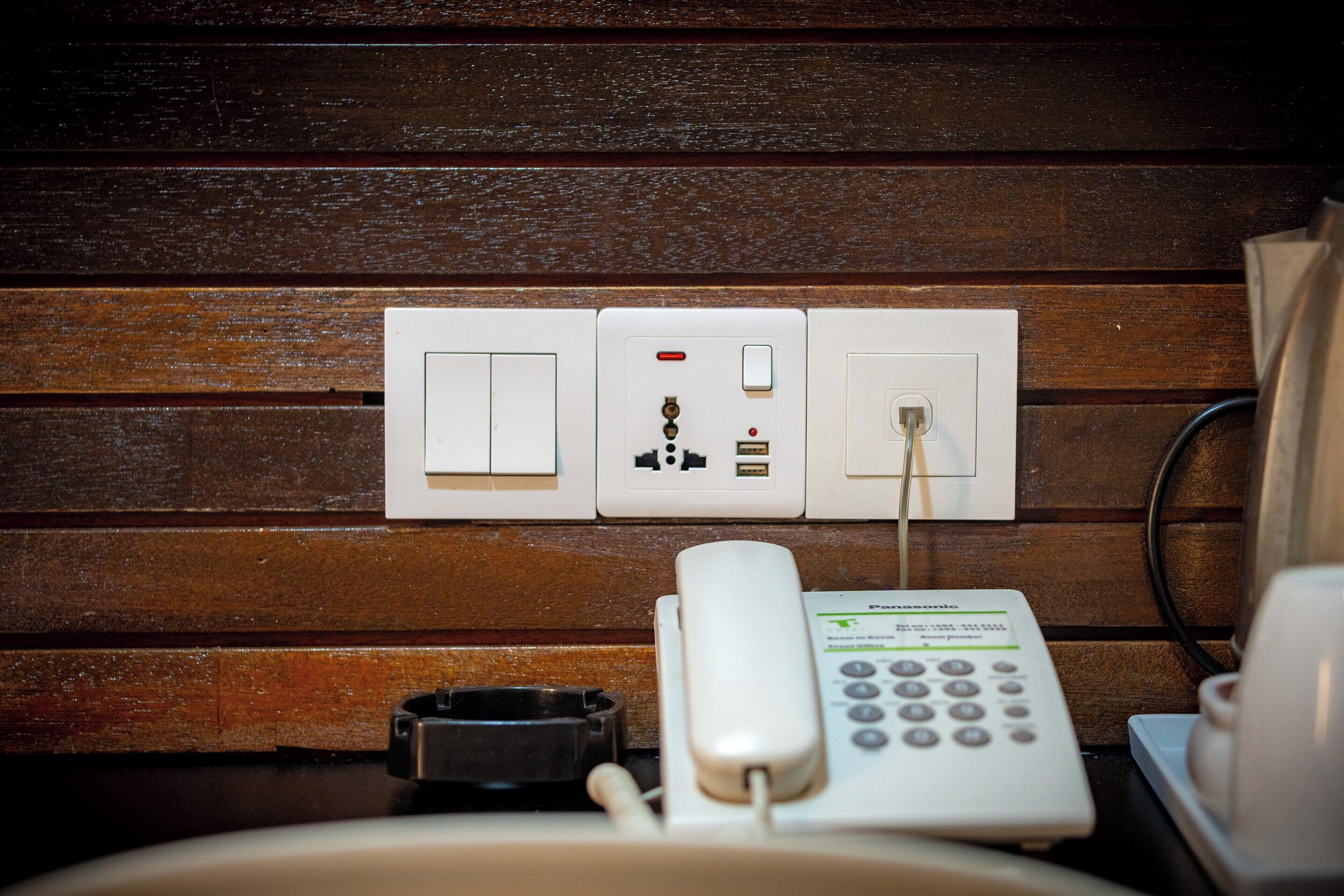 Un panneau électrique fixé au mur, avec un téléphone et une poubelle à proximité.