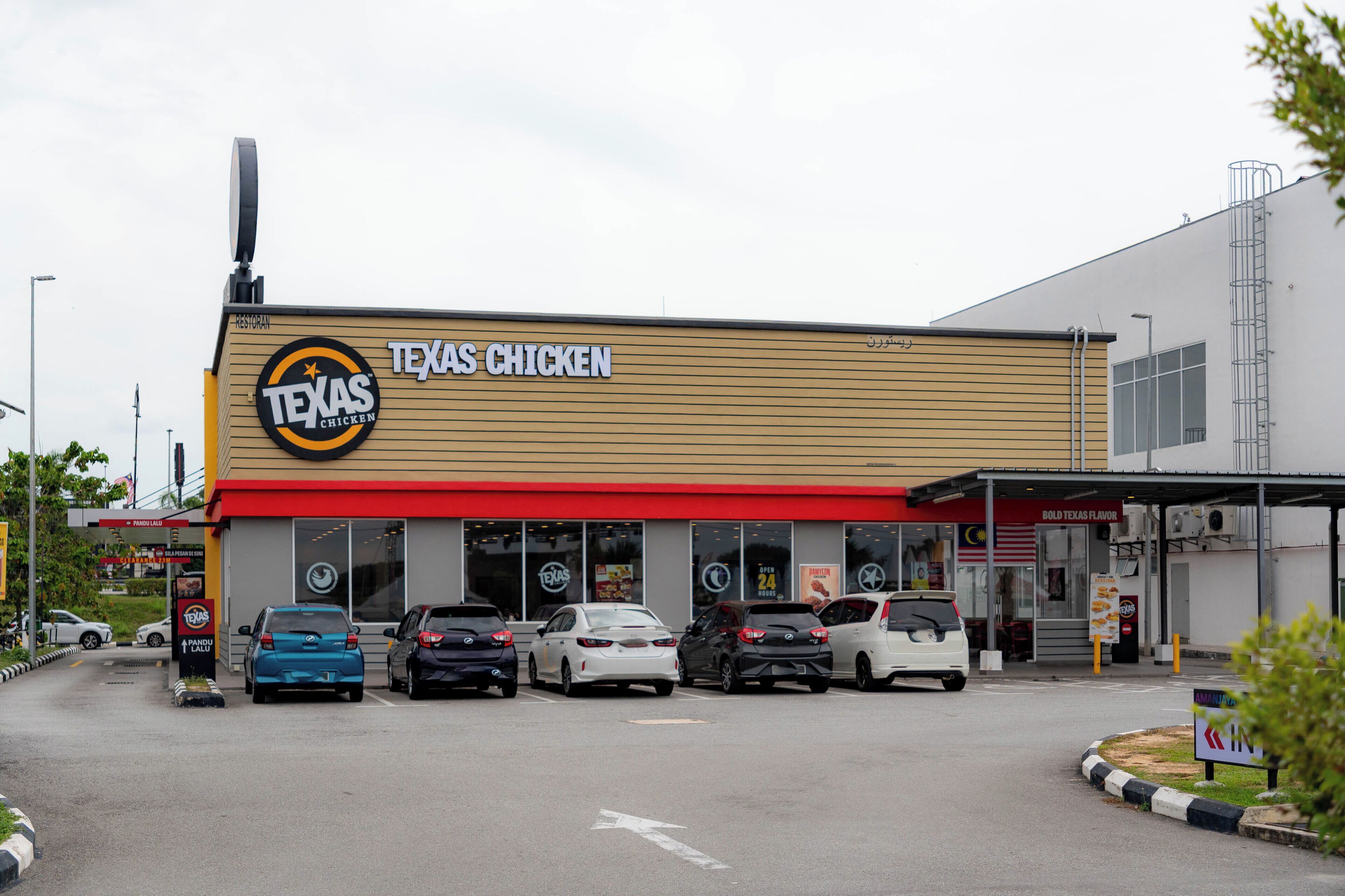 A Texas Chicken restaurant with a red awning and multiple cars parked in front.