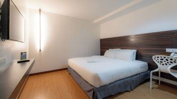 Ein Hotelzimmer mit Bett, Schreibtisch, Stuhl und Flachbildfernseher.