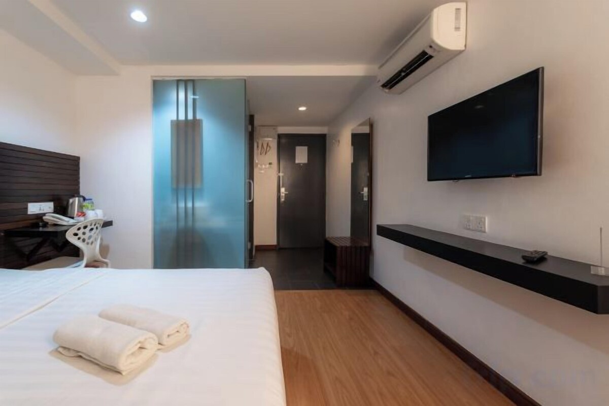A hotel room with a bed, a desk, a chair, a television, and a bathroom door.