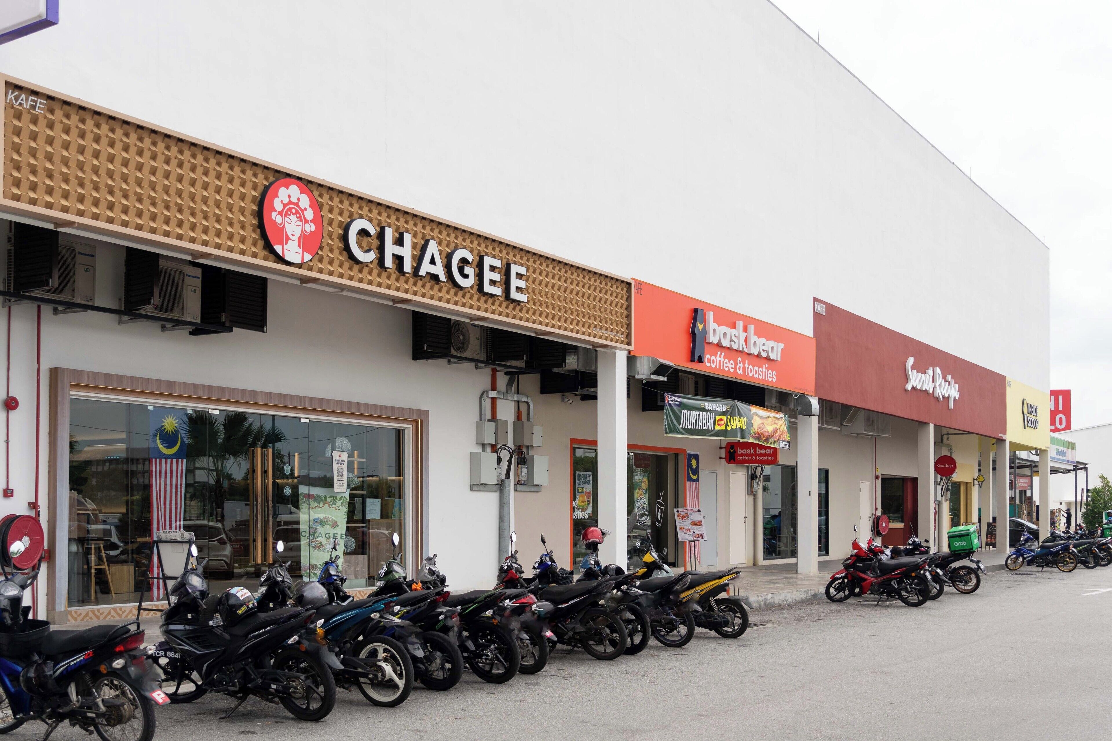 A row of motorcycles parked in front of a building with a sign that reads "Chagee".