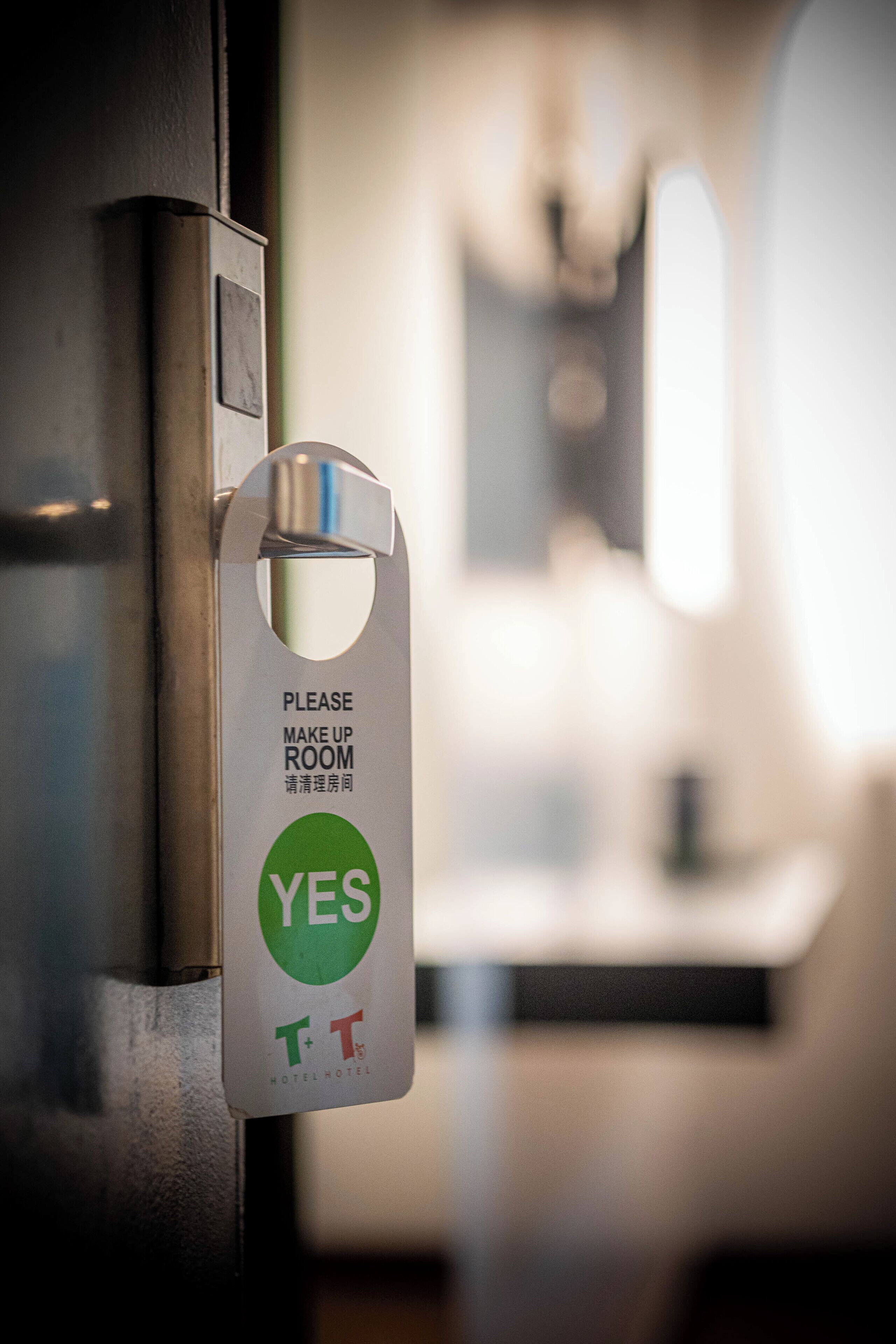 Eine Hotelzimmertür mit einem Schild, das dazu auffordert, das Zimmer abzureinigen.