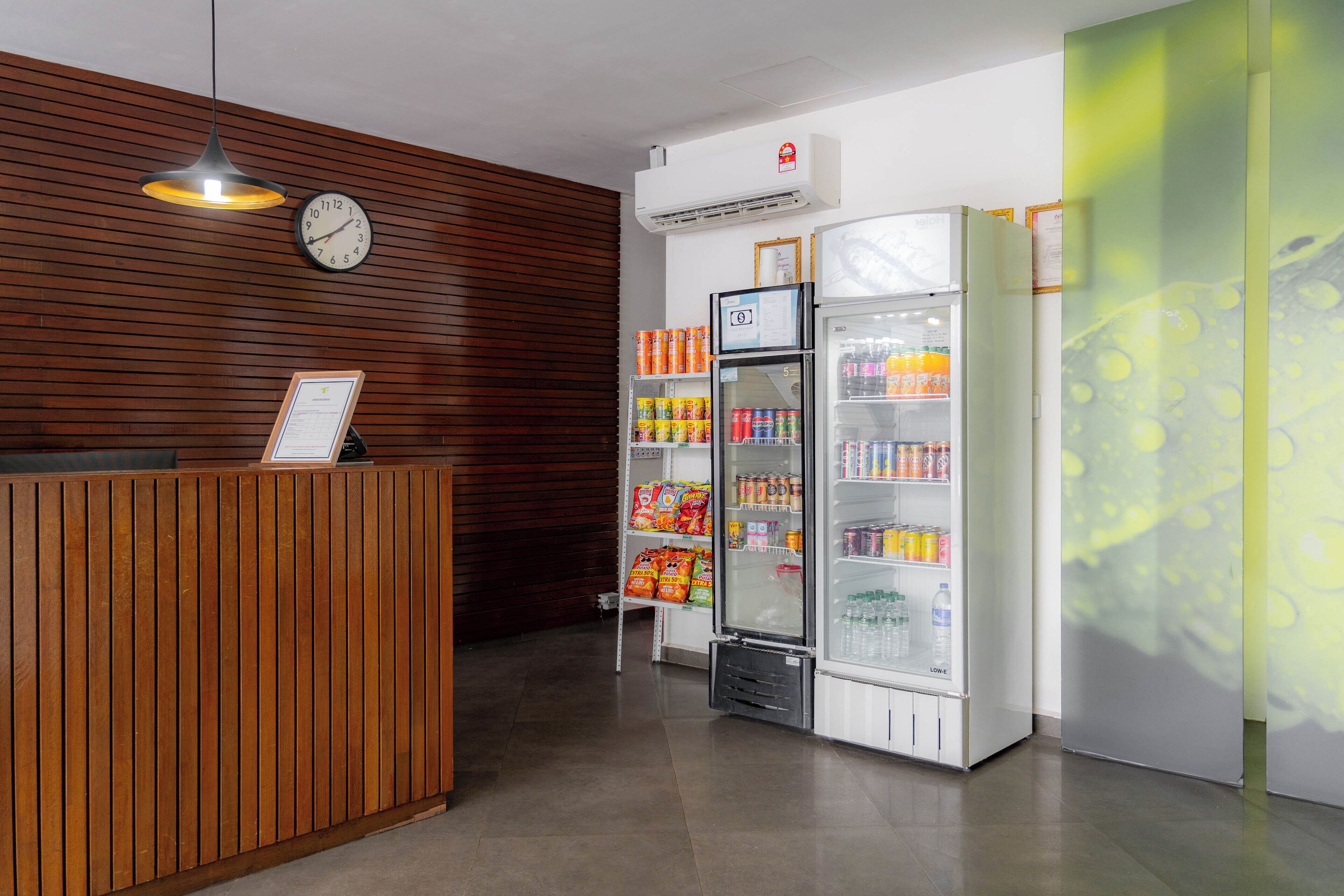 A reception area with a wooden reception desk, a wall-mounted clock, and a vending machine stocked with snacks and drinks.