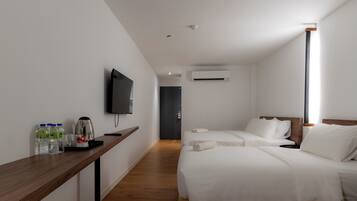 Habitación de hotel con dos camas, un televisor montado en la pared, una cafetera y un dispensador de agua en la mesita de noche.