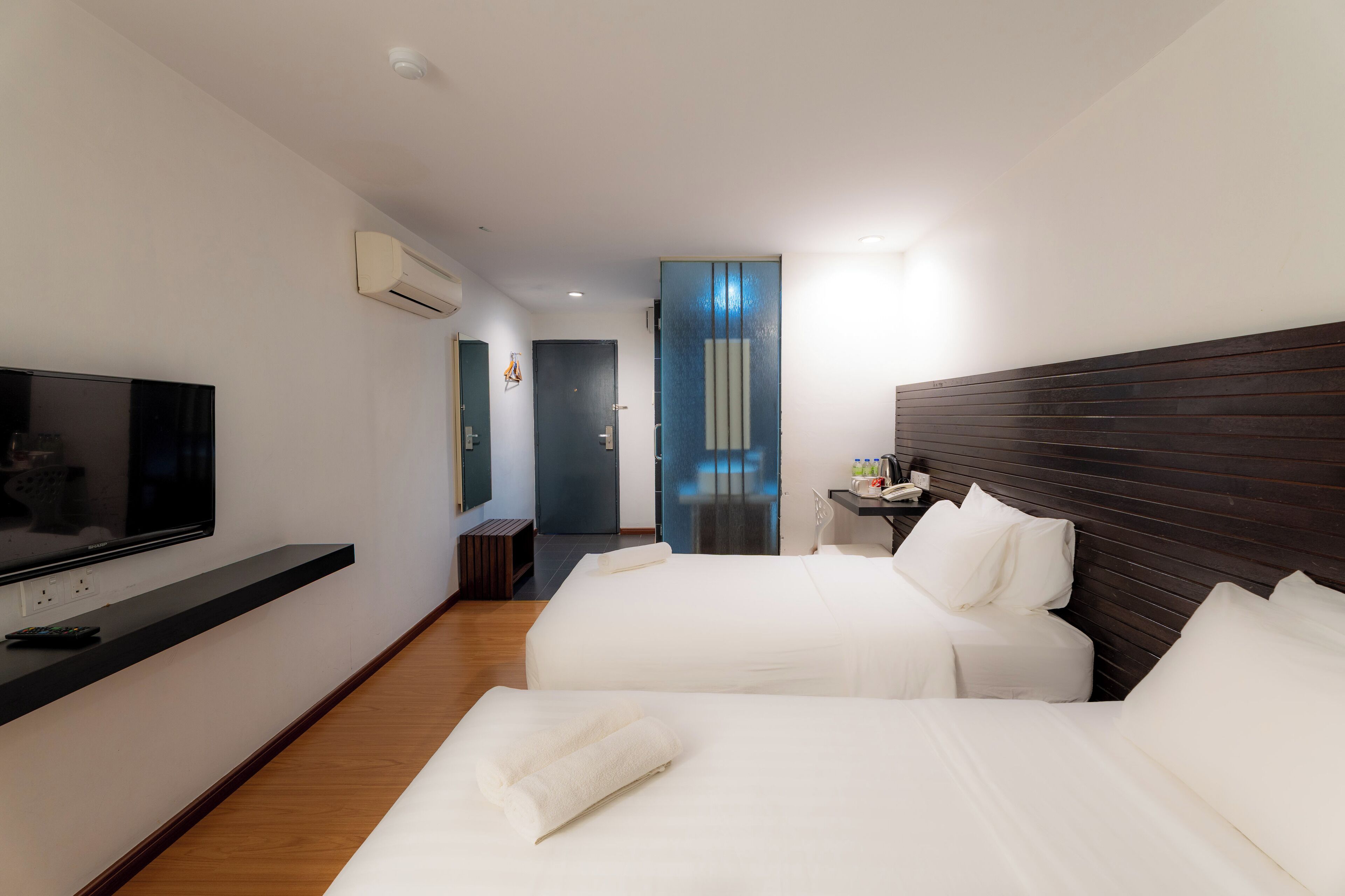 A hotel room with two beds, a TV, a desk, and a bathroom door.