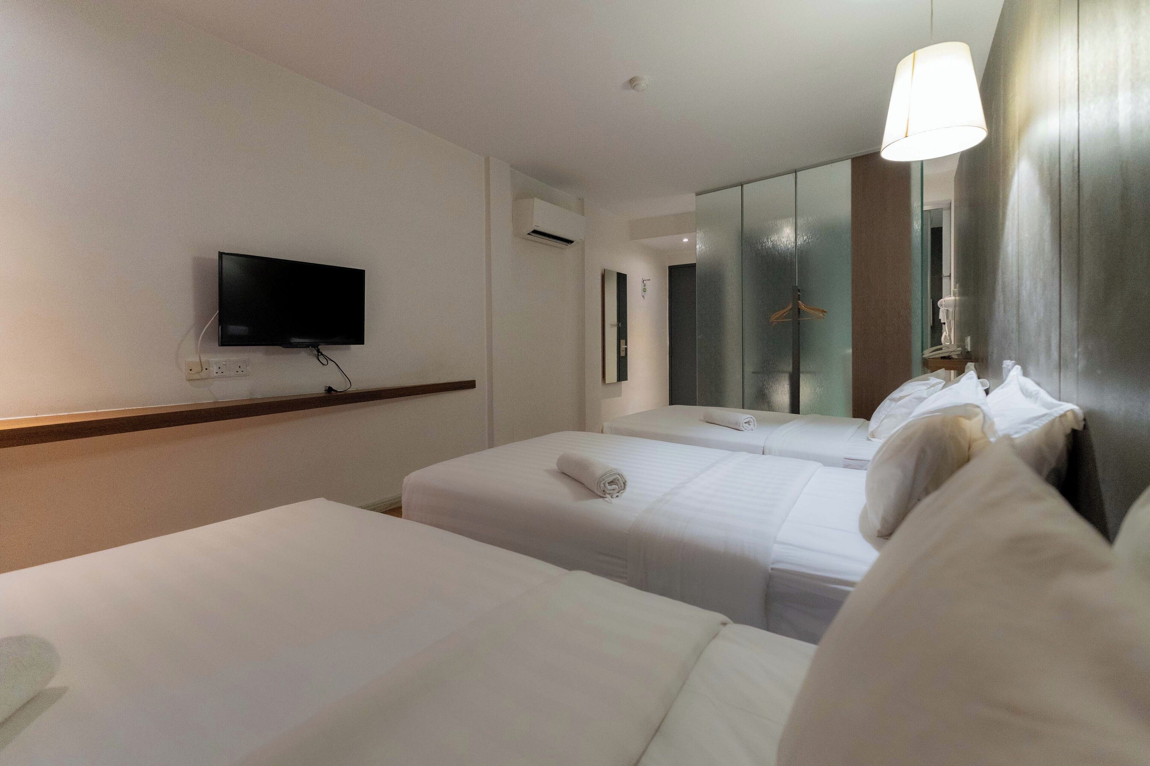 Camera d'albergo con due letti, una TV a schermo piatto montata a parete, uno specchio e un lampadario.
