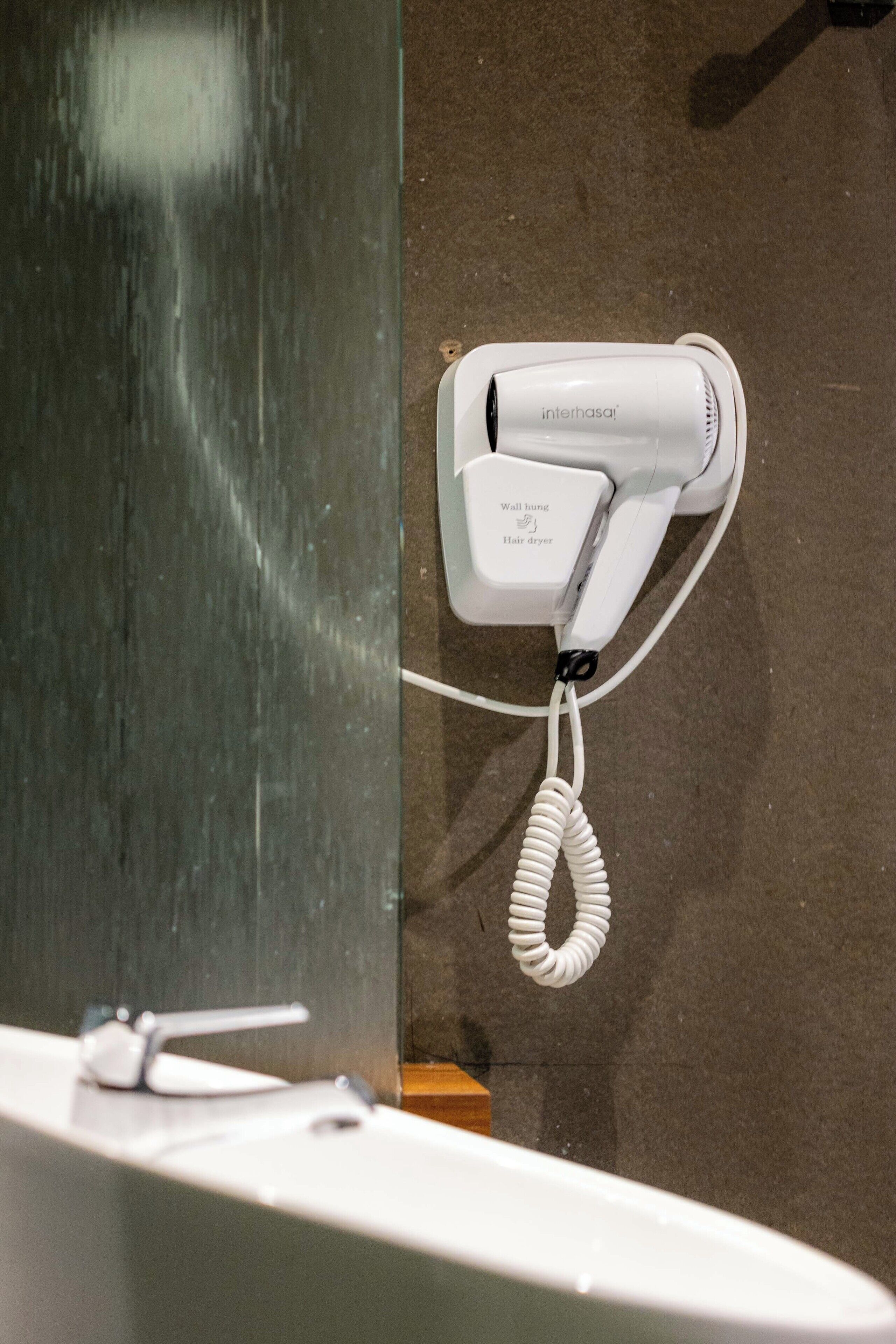 Un secador de pelo fijado a la pared cerca de un lavabo de baño.