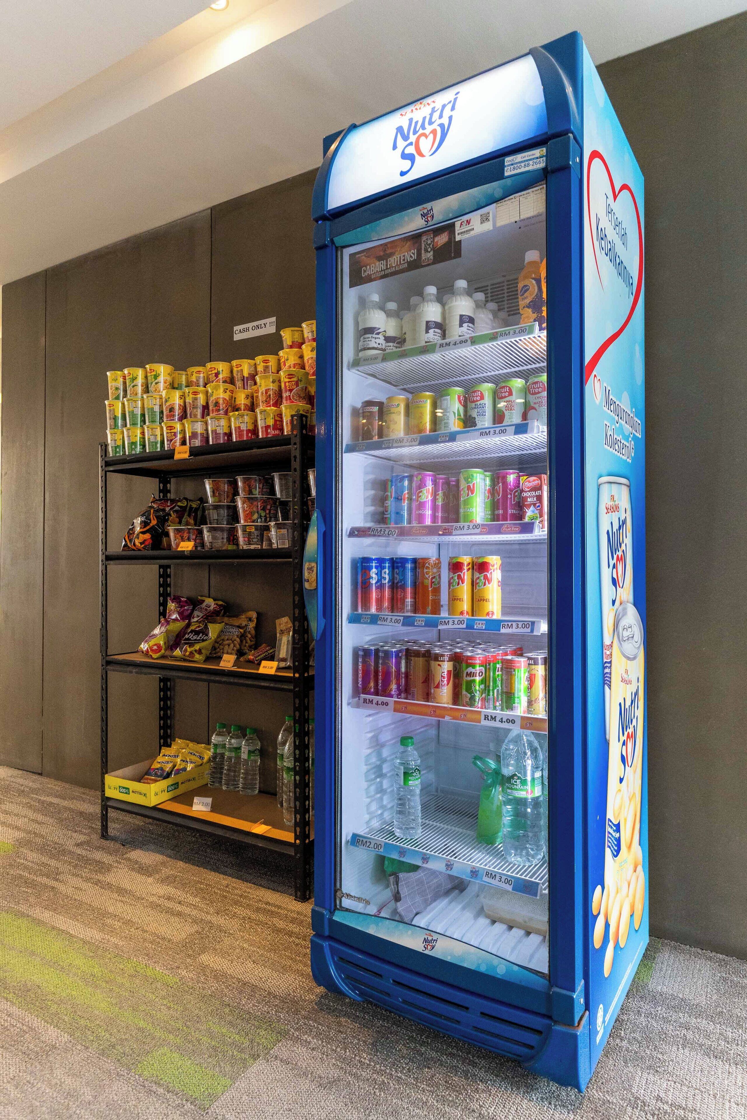 A vending machine stocked with various beverages and snacks, and a shelf unit with packaged goods.