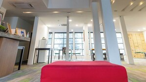En modern inredning med ett stort, öppet centralt utrymme, flera våningsplan och en röd sittgrupp.