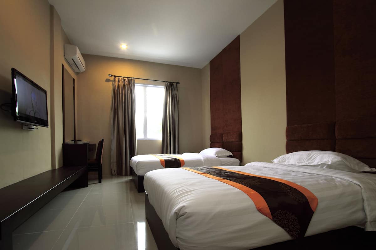 A hotel room with two beds, a flat-screen TV mounted on the wall, a desk, and a window with curtains.