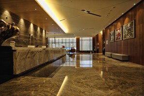 A modern lobby with a marble reception desk, wooden paneling, and artwork on the walls. - Hotel Intrendy (New Taipei City)