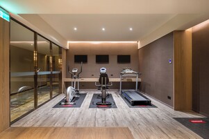 Un gimnasio moderno con máquinas de cardio, equipo de entrenamiento de pesas y una cinta de correr.