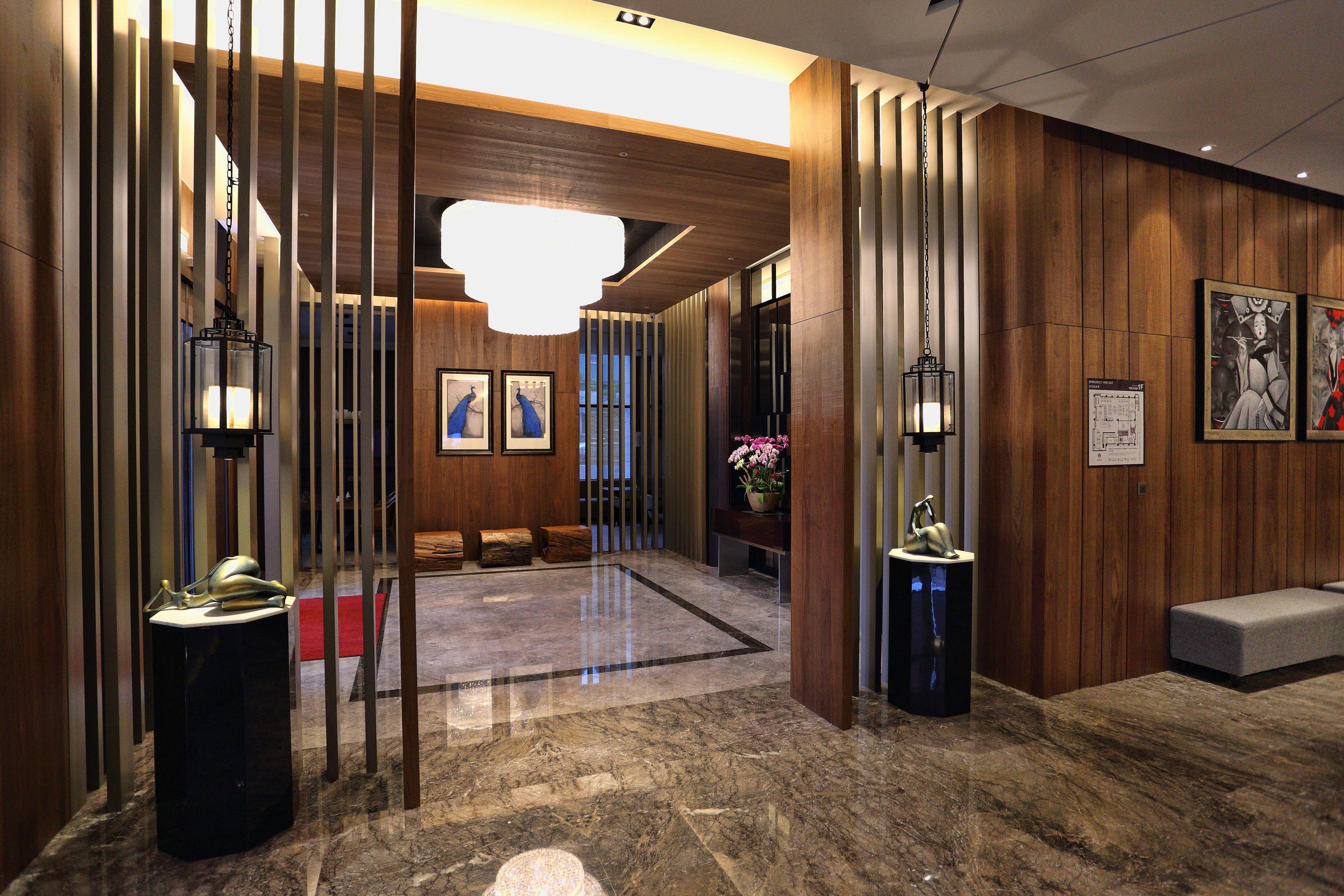 A lobby with wooden paneling, a marble floor, and a reception desk with a red carpet.